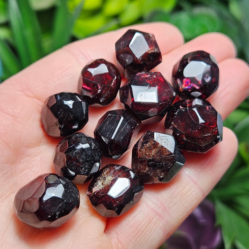 May include: A collection of ten faceted red garnet gemstones. The garnets are polished and have a deep red color with a slight shine.
