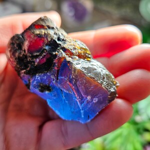 May include: A large piece of blue amber with red and gold inclusions. The amber is rough and has a natural, unpolished finish.