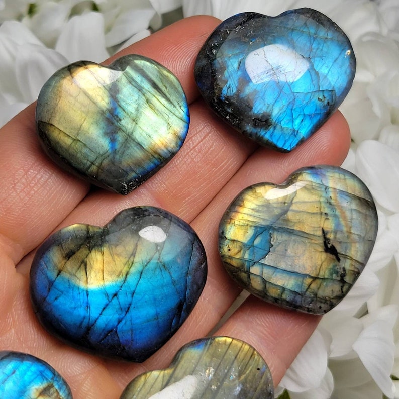 May include: Five heart-shaped labradorite crystals with iridescent blue and gold colors. The crystals are polished and smooth.