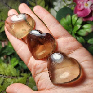 Puede incluir: Tres cristales en forma de coraz&oacute;n, uno marr&oacute;n claro, uno marr&oacute;n oscuro y uno transparente con un tono marr&oacute;n claro. Los cristales son lisos y pulidos.
