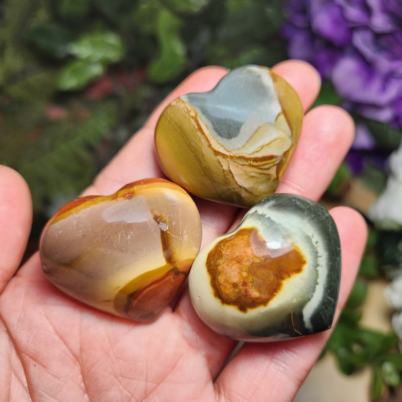 May include: Three heart-shaped polished stones with brown, yellow, white, and green patterns.