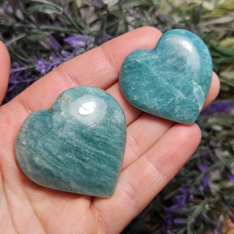 Peut inclure: Deux pierres d'amazonite en forme de c&oelig;ur de couleur verte. Les pierres sont lisses et polies, avec une couleur vert clair et des stries blanches.