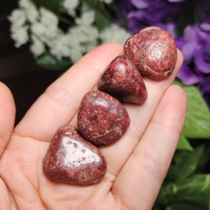 May include: Four tumbled red jasper stones with white and brown markings. The stones are smooth and polished.