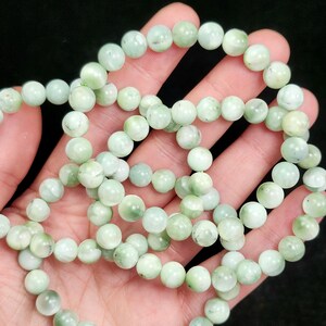 Peut inclure: Collier de perles de pierres pr&eacute;cieuses vert clair. Les perles sont rondes et pr&eacute;sentent un aspect l&eacute;g&egrave;rement marbr&eacute;, avec des variations de couleur du vert p&acirc;le au vert moyen. Les perles sont enfil&eacute;es, pour un collier ou bracelet.