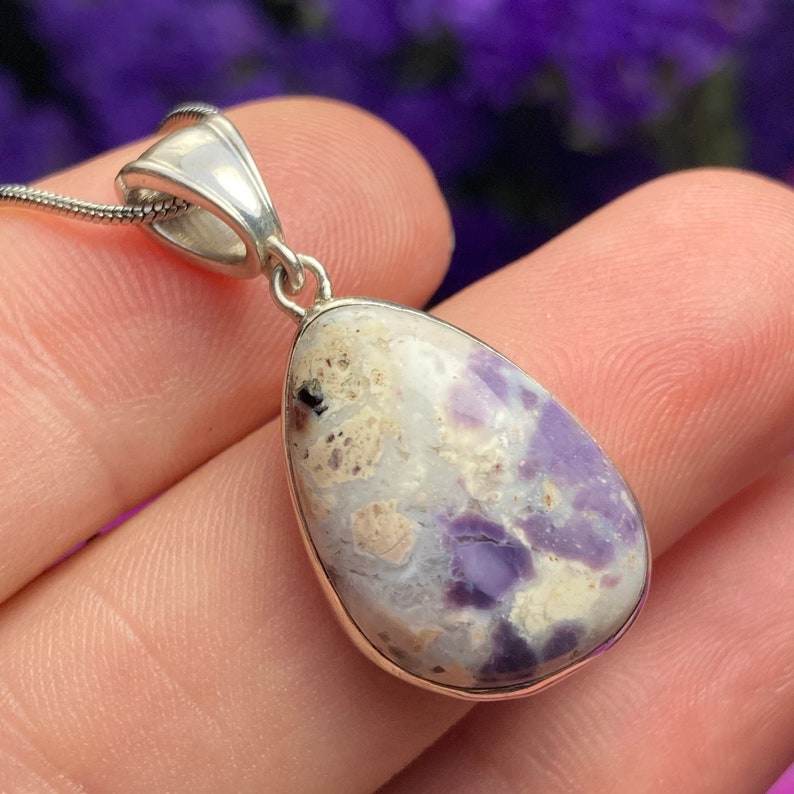 May include: A silver pendant with a teardrop-shaped purple and white opal stone.