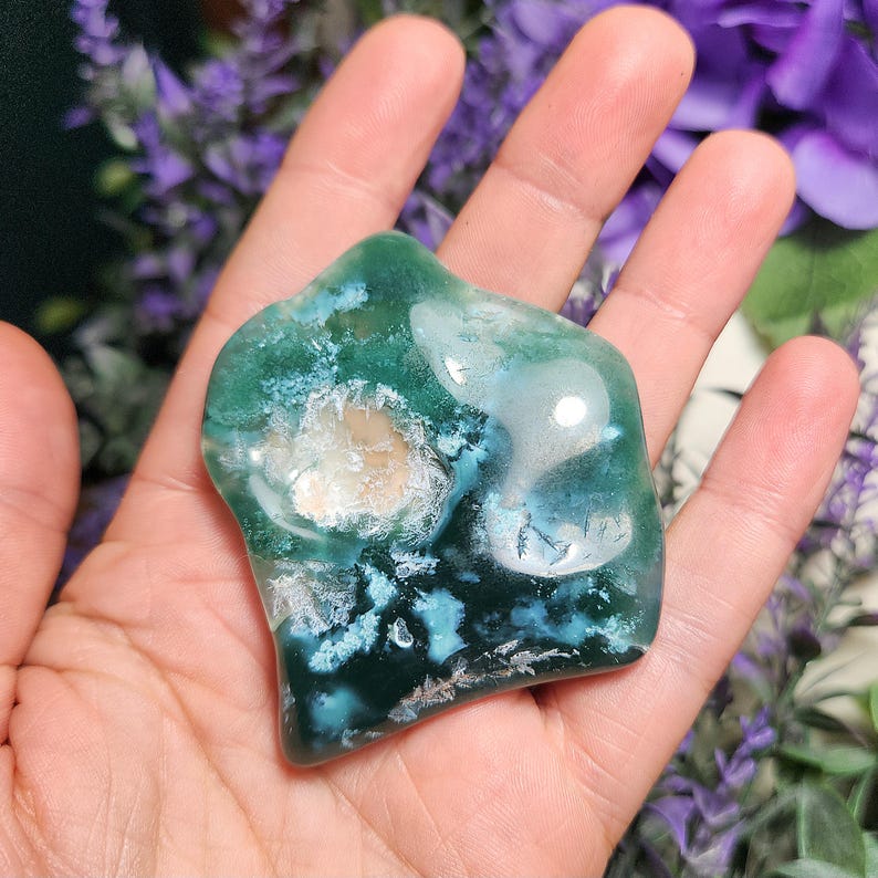 May include: A green, blue, and white agate stone with a smooth, polished surface. The stone has a unique, swirling pattern and is a natural, organic shape.