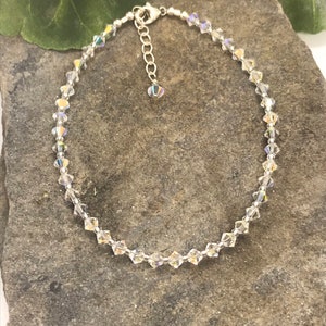 Pu&ograve; includere: Un delicato braccialetto per caviglia in argento con una catena di cristalli e un piccolo ciondolo di cristallo. Il braccialetto &egrave; fatto di piccoli cristalli trasparenti che brillano alla luce.