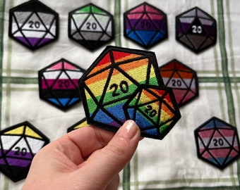 Könnte beinhalten: Ein Set aus neun gestickten Bügeletiketten in Regenbogen-, Schwarz-, Weiß- und Grautönen in Form von zwanzigseitigen Würfeln. Jedes Etikett trägt die Nummer "20" aufgedruckt.