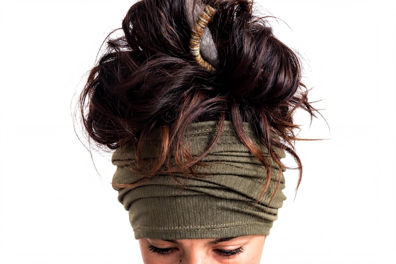 A close-up view of a person's head, with their hair styled in a messy bun and wearing a green headband.
