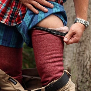 Puede incluir: Unos leggings térmicos de color granate con un forro interior suave y afelpado, usados debajo de unos pantalones cargo de color tostado con un cinturón negro y una camisa de franela a cuadros rojos, azules y blancos. Tienen una costura negra.