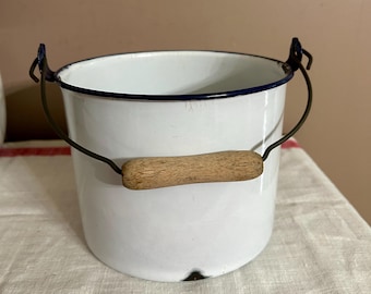 Cubo de cerámica esmaltada blanca vintage con ribete azul, asa de alambre y mango de madera, decoración rústica para el hogar y la cocina de una casa de campo.