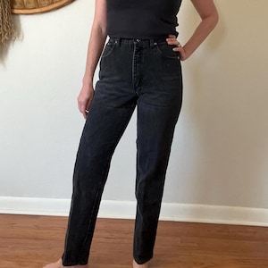 May include: Black denim jeans with a classic straight-leg fit. The jeans have a high waist and a button and zipper closure. The dark wash denim is a versatile wardrobe staple.