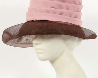 May include: A pink and brown hat with a wide brim and a ruffled crown. The hat is made of a soft, lightweight fabric and has a delicate, feminine look.