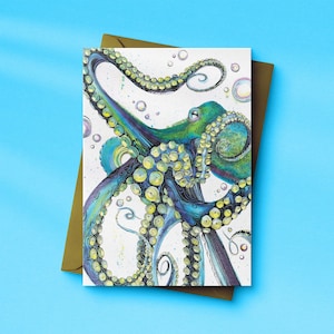 May include: A greeting card with an octopus illustration in blue, green, and yellow. The octopus has multiple tentacles and is surrounded by bubbles. The card is on a brown envelope against a blue background.