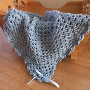 May include: A light blue crocheted baby blanket with a light blue ribbon tied at the bottom.