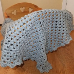 May include: A light blue crocheted baby blanket with a scalloped edge.