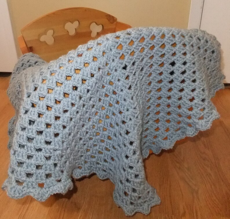 May include: A light blue crocheted baby blanket with a scalloped edge.