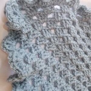 May include: A light blue crocheted shawl with a lacy, openwork design. The shawl has a scalloped edge.