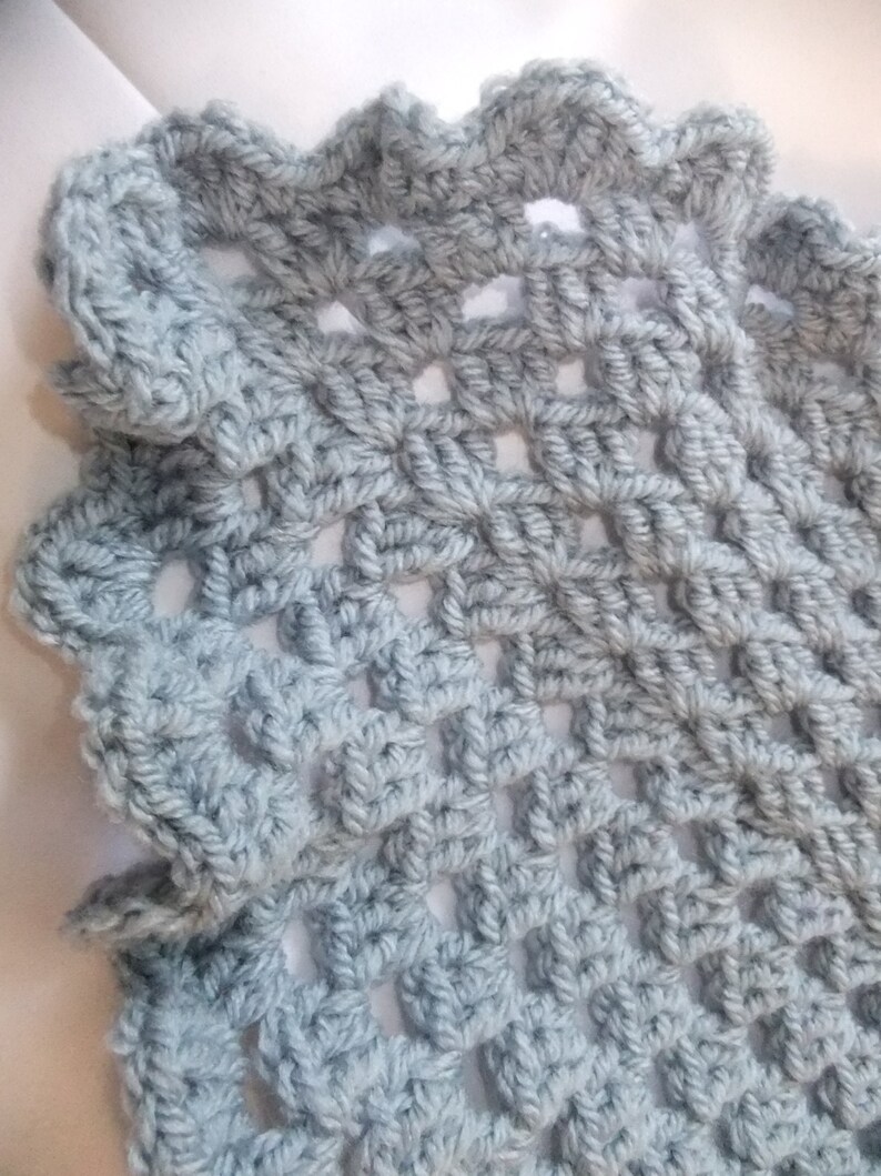 May include: A light blue crocheted shawl with a lacy, openwork design. The shawl has a scalloped edge.