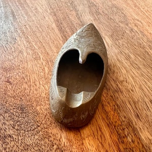 May include: A brass ashtray shaped like a shoe with an intricate floral design.