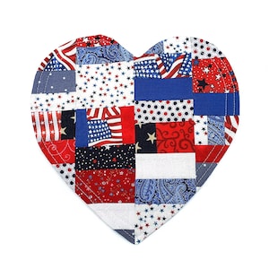 May include: A heart-shaped patchwork item with a patriotic theme. The design incorporates red, white, and blue fabrics with star, flag, and paisley patterns. The item is likely a decorative piece or a small quilt.