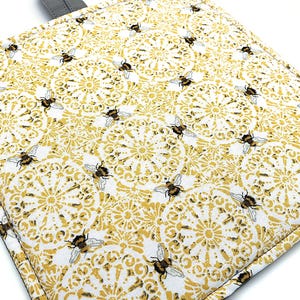 May include: A white ceramic mug with a black handle and the text "But First, Coffee" in a bold, black font. The mug is set against a blurred background, suggesting a cozy setting.