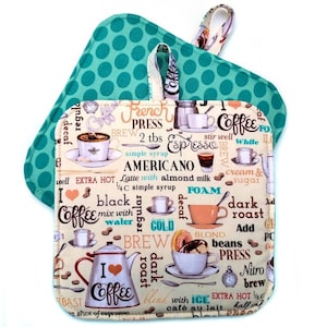 May include: Two coffee-themed pot holders. The top one is teal with white polka dots. The bottom one is beige with coffee-related graphics and text, including "Espresso," "Americano," and "I love coffee." Both have a loop for hanging.
