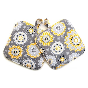 May include: A pair of gray and yellow floral pot holders with a loop handle.