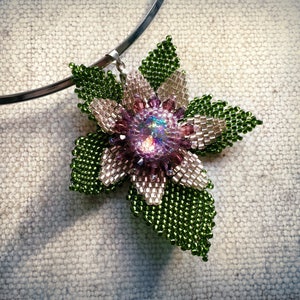 May include: A beaded flower pendant necklace with a green and white flower and a iridescent purple center. The necklace is on a silver chain.
