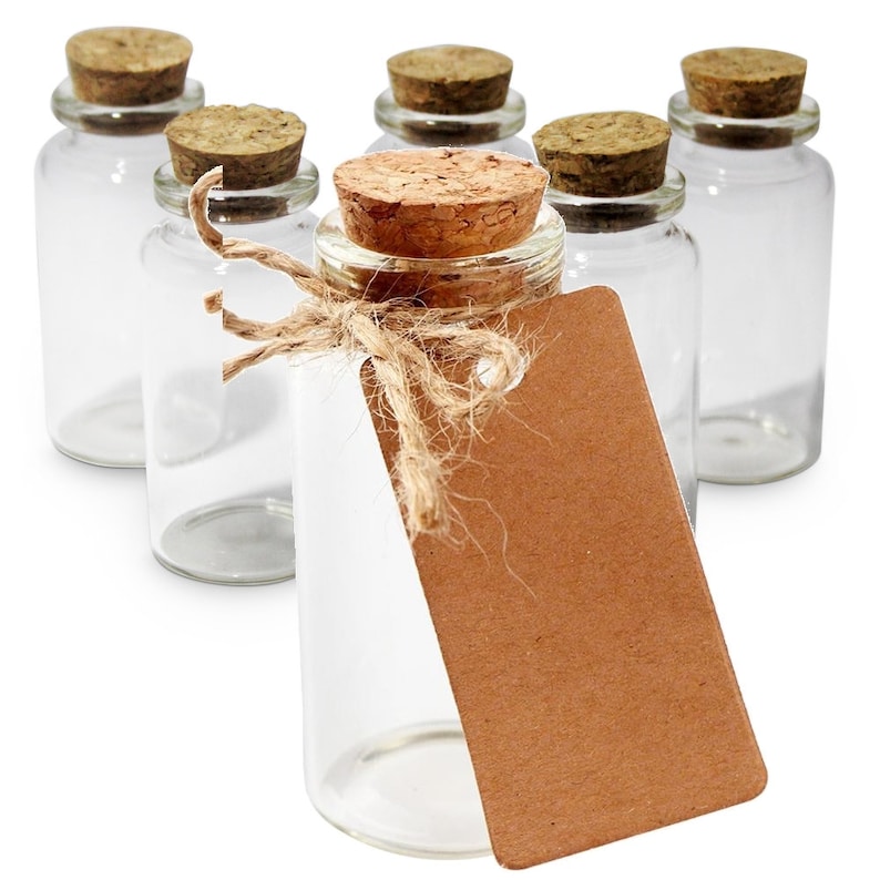 May include: Six clear glass bottles with cork stoppers. One bottle has a brown paper tag tied with twine.