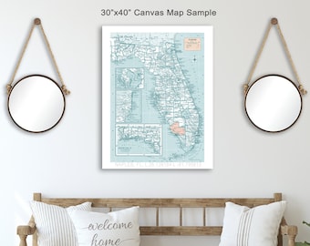 Könnte beinhalten: Eine hellblaue Leinwandkarte von Florida im Vintage-Stil. Die Karte ist gerahmt und hängt an einer weißen Wand über einer Holzbank mit Kissen. Die Karte ist 76 cm x 102 cm groß.