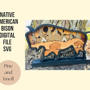 May include: A wooden cutout of a bison with a forest scene inside. The bison is black and the forest scene is made of different shades of brown and green wood. The bison is standing on a black base. The text "Pine and Knoll" is visible in the image.