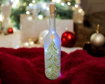 Hand painted bottle with fairy lights, frosted white, snow covered pine trees, lights included .