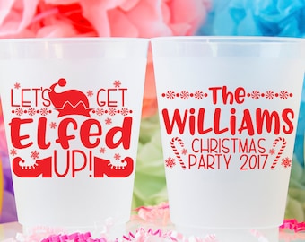 May include: Two white plastic cups with red text. The first cup says "Let's Get Elfed Up!" with a red elf hat and boots. The second cup says "The Williams Christmas Party 2017" with candy canes and snowflakes.