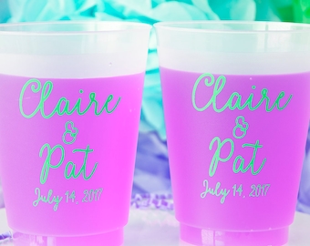 Könnte beinhalten: Zwei durchsichtige Plastikbecher mit mattem Finish. Die Becher sind mit einer hellvioletten Flüssigkeit gefüllt und haben den Text "Claire & Pat July 14, 2017" in Grün aufgedruckt.