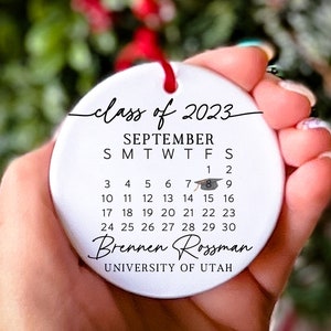 May include: White ceramic bauble with the text "class of 2023" and a calendar for September with a graduation cap icon on the 8th. The text "Brennen Rossman" and "UNIVERSITY OF UTAH" are also included.