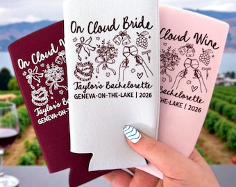 May include: Three foam can coolers in burgundy, white, and light pink. Each features black or white line art of a bouquet, wine glasses, and bells with the text On Cloud Bride, Taylor's Bachelorette, and Geneva-on-the-Lake 2026 printed on them.