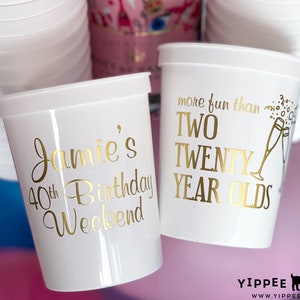 May include: White plastic cups with gold lettering. One cup says "Jamie's 40th Birthday Weekend" and the other says "More fun than two twenty year olds".