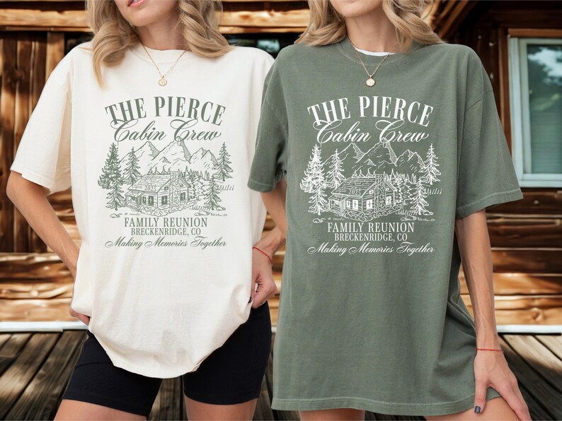 Pu&ograve; includere: Due magliette oversize, una color crema e una verde oliva, con una grafica di un rifugio di montagna e il testo "THE PIERCE Cabin Crew FAMILY REUNION BRECKENRIDGE, CO Making Memories Together". Le magliette sono indossate da una persona.
