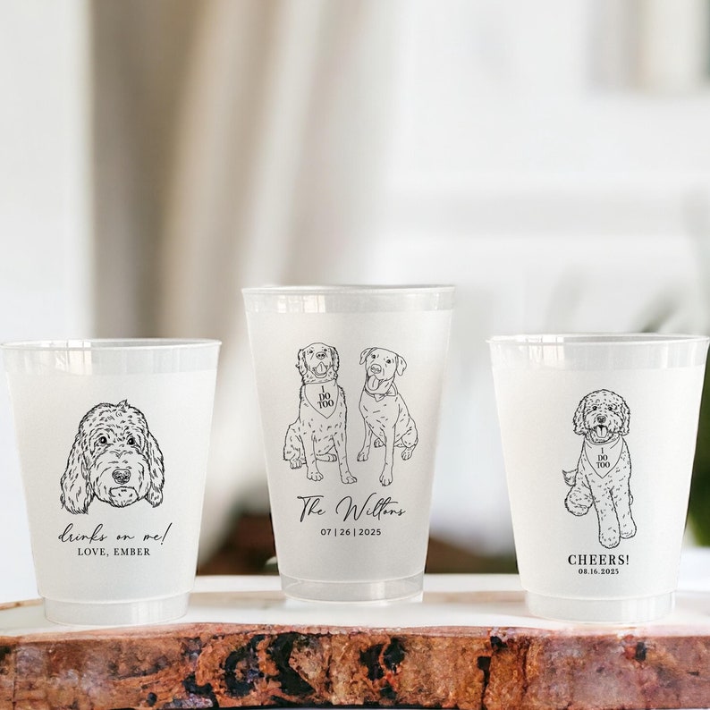 May include: Three clear plastic cups with black line drawings of dogs and text. The cup on the left has a doodle of a dog and the text 'Drinks on me! Love, Ember'. The middle cup has two doodles of dogs and the text 'The Willens 07|26|2025'. The cup on the right has a doodle of a dog and the text 'Cheers! 08.16.2025'.