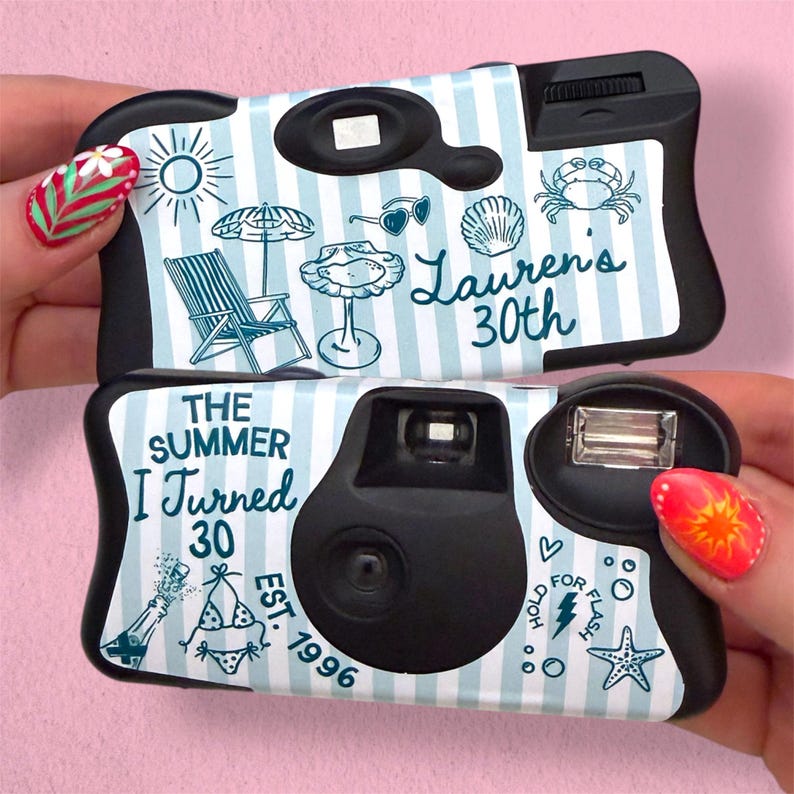 May include: Two disposable cameras with light blue and white vertical stripes. The top camera features a sun, umbrella, chair, shell, crab, and text reading Lauren's 30th. The bottom camera features text reading The Summer I Turned 30 Est. 1996, a bikini, champagne, and a starfish.