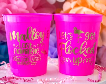 May include: Two pink plastic cups with gold lettering. One cup says "Mallory's Last Flamingo Cabo San Lucas November 2017". The other cup says "Let's get Flocked Up".