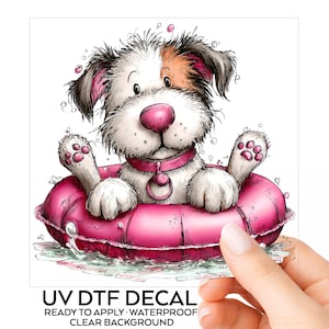 May include: A UV DTF decal featuring a cartoon dog with white and brown fur, a pink nose, and a pink collar, sitting inside a bright pink inflatable swim ring surrounded by water bubbles. The text reads UV DTF DECAL READY TO APPLY WATERPROOF CLEAR BACKGROUND.