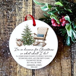 May include: White ceramic Christmas bauble featuring a rocking chair and a Christmas tree. The ornament includes the text "I'm in heaven for Christmas so what shall I do? I'll come down to earth to spend it with you. So save me a seat, just one empty chair. You may not see me, but I will be there. Grandpa Jones 1950-2022"