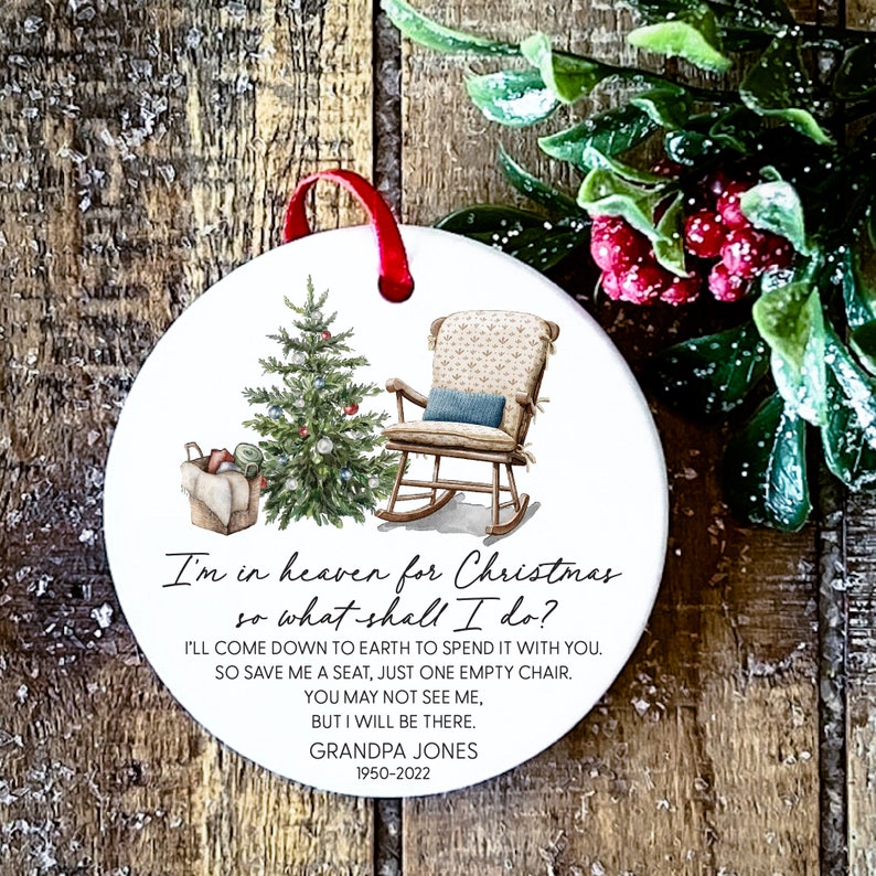 May include: White ceramic Christmas bauble featuring a rocking chair and a Christmas tree. The ornament includes the text "I'm in heaven for Christmas so what shall I do? I'll come down to earth to spend it with you. So save me a seat, just one empty chair. You may not see me, but I will be there. Grandpa Jones 1950-2022"