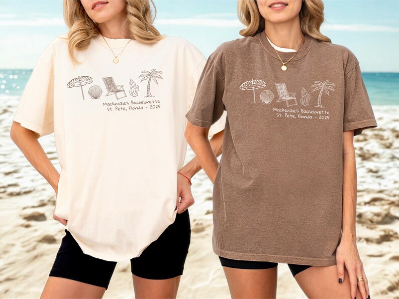 May include: Two oversized t-shirts, one cream and one brown, featuring a beach-themed graphic. The graphic includes an umbrella, beach ball, chair, seashell, and palm tree, with the text "Mackenzie's Bachelorette St. Pete, Florida - 2025".