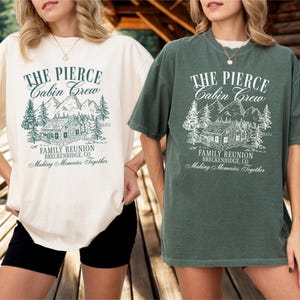 Pu&ograve; includere: Due magliette oversize, una color crema e una verde, ciascuna con una stampa grafica. La stampa presenta il testo "THE PIERCE Cabin Crew" sopra un'illustrazione di una baita, con "FAMILY REUNION BRECKENRIDGE, CO" e "Making Memories Together" sotto.