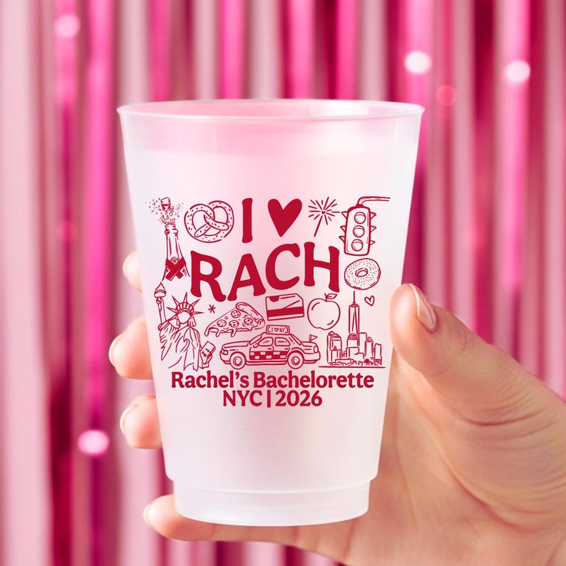 May include: A frosted plastic cup featuring red printed graphics including a pretzel, a heart, a traffic light, the Statue of Liberty, a pizza slice, a taxi, an apple, and the text I LOVE RACH, Rachel's Bachelorette, and NYC 2026.