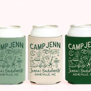 May include: Three foam can coolers in sage green, beige, and forest green. Each features the text CAMP JENN, Jenna's Bachelorette, and ASHEVILLE, NC, with illustrations of a lantern, campfire, guitar, hiking boot, and a flag labeled cheers 2025.