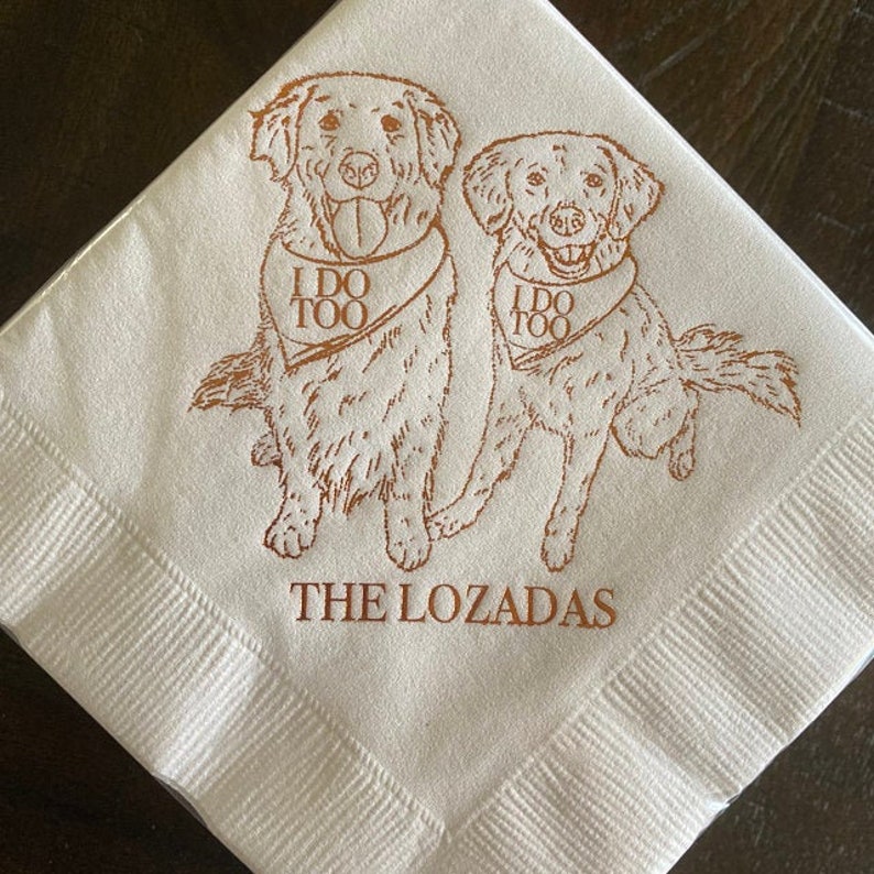 May include: Two golden retriever dogs wearing bandanas with the text "I do too" on a white napkin with the text "The Lozadas" printed below.